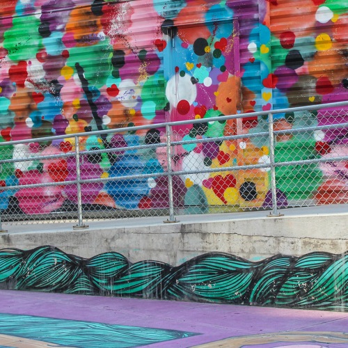 Neighborhood Colorful heart mural on corrugated metal wall with graffiti accents near Lakewood apartments.