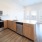 Modern kitchen with stainless steel appliances, white cabinets, and wood-grain accents in Lakewood apartment.