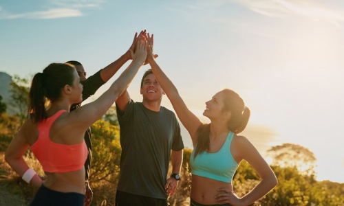 friends high-fiving on top of a mountain